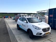 waterstofauto bij gemeentewerf Groningen. Op de achtergrond zonnepanelen waarmee groene waterstof wordt geproduceerd.