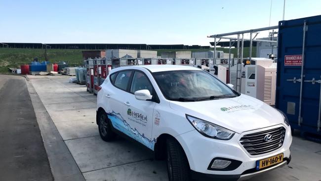 waterstofauto bij gemeentewerf Groningen. Op de achtergrond zonnepanelen waarmee groene waterstof wordt geproduceerd.